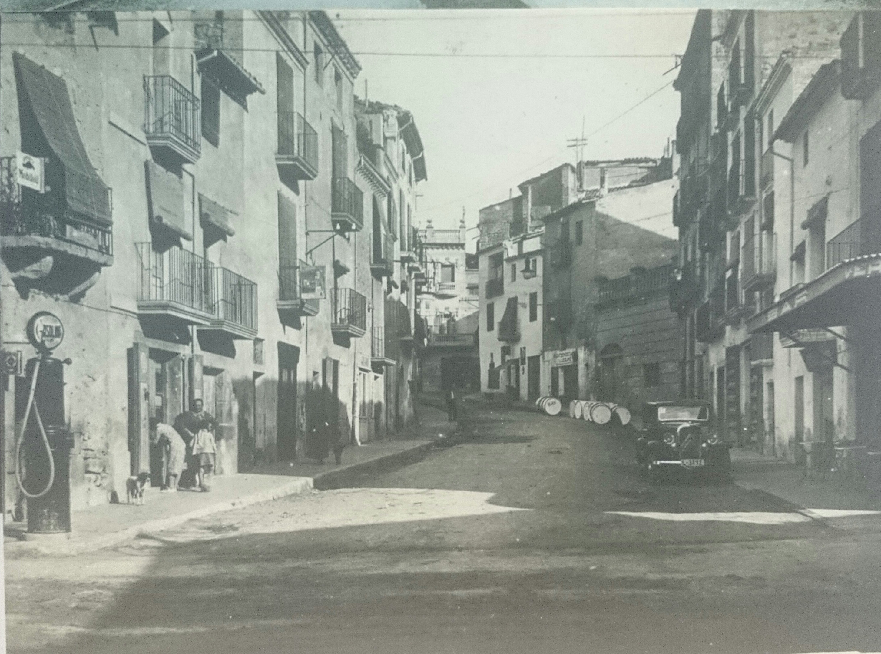 Fotografia antiga del carrer la bassa amb cotxes i una gasolinera antiga